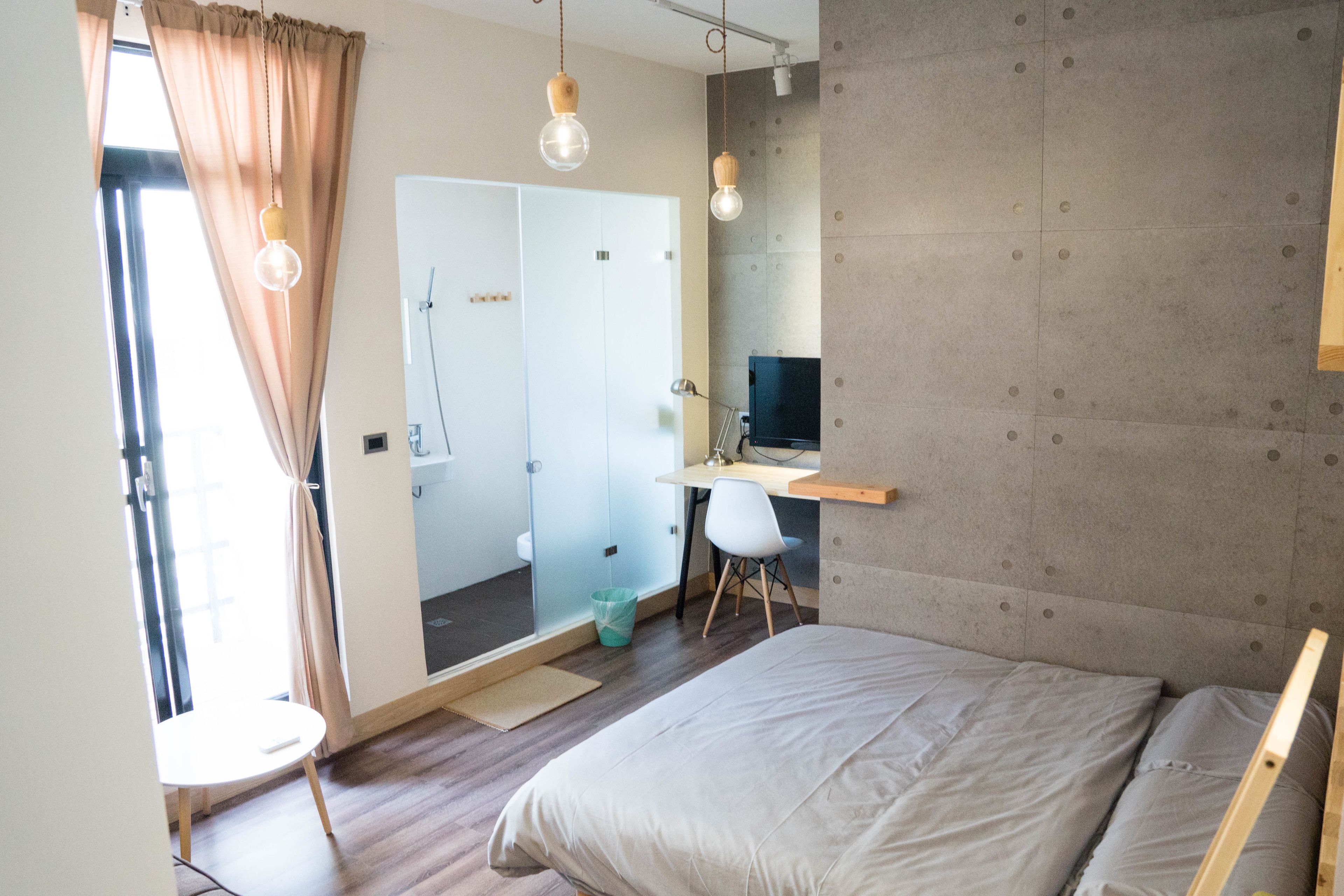 Un dormitorio moderno con cama, escritorio y zona de ducha.