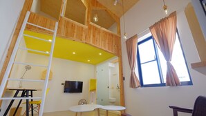 A room with a lofted sleeping area, a television, a small table with chairs, and a window with curtains. - Hinoki Mansion (Tainan)