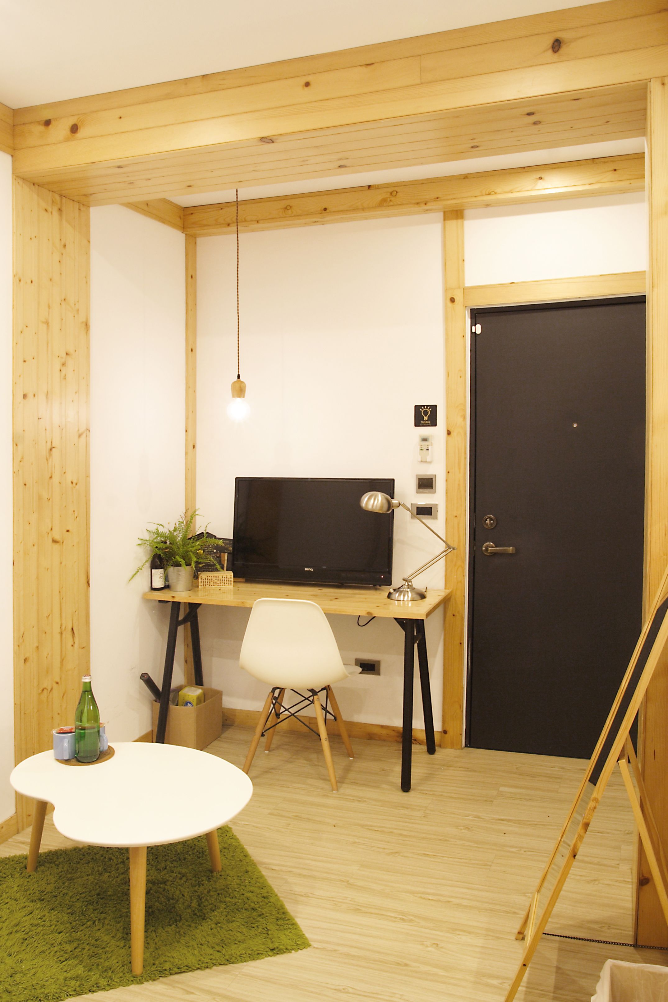 Una habitación pequeña y acogedora con un escritorio de madera, una silla, una computadora y una puerta.