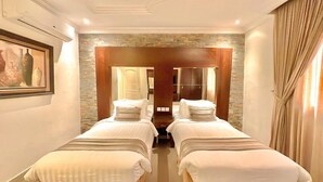 Ein Hotelzimmer mit zwei Betten, einer Steinsäule und einem gerahmten Bild an der Wand.
