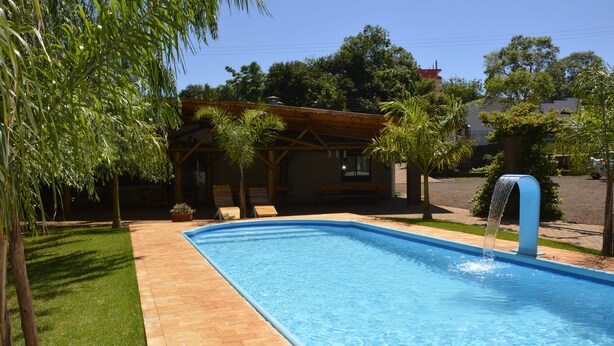 A rectangular swimming pool with a clear blue water surface, surrounded by a brick deck. - Hotel Salzburgo (Presidente Franco)