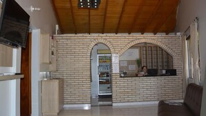 A reception area with a brick wall, a refrigerator, a vending machine, and a counter with a computer. - Hotel Salzburgo (Presidente Franco)