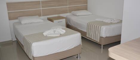 Una habitación de hotel con dos camas, una mesita de noche y un cabecero de madera.