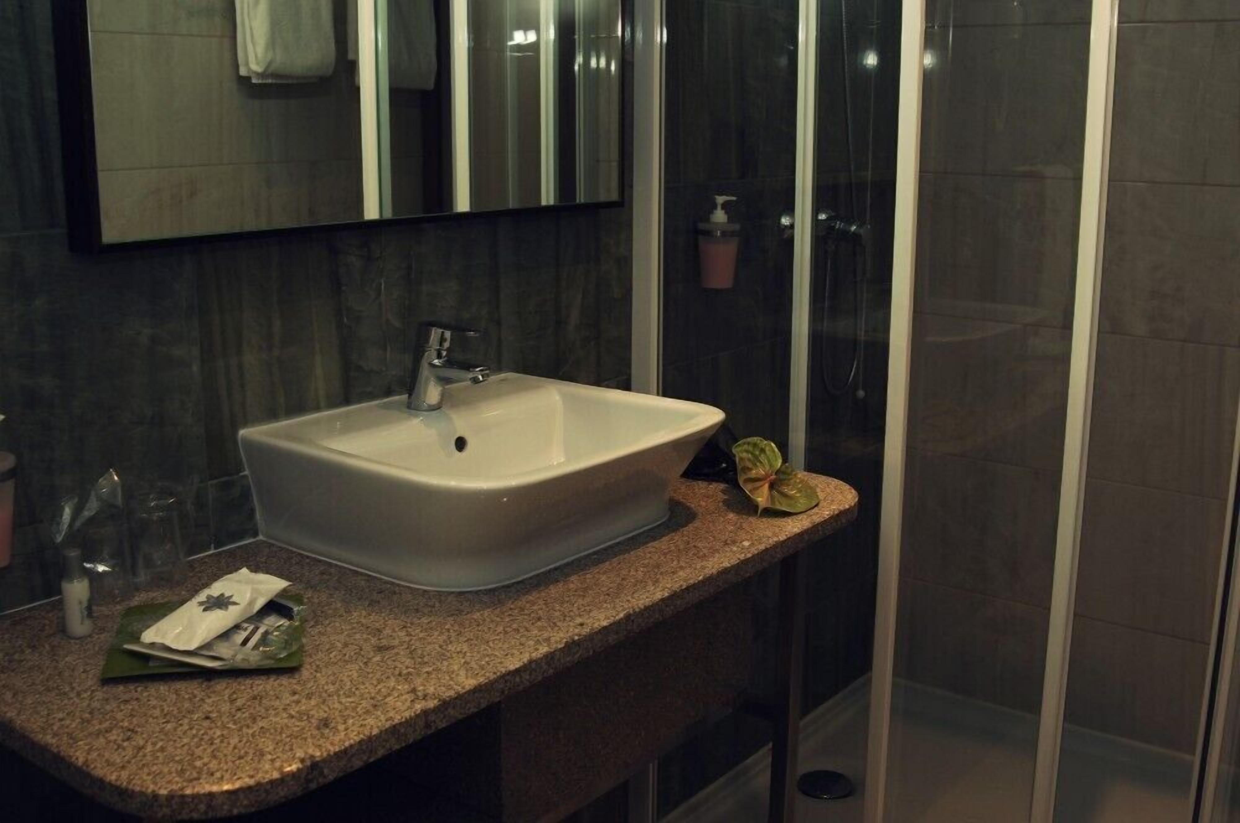 A bathroom with a white sink, a mirror, and a glass shower enclosure.