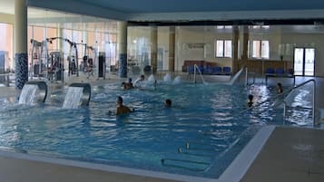 Una piscina interior con varias pistas, equipo de ejercicio y una zona de descanso.