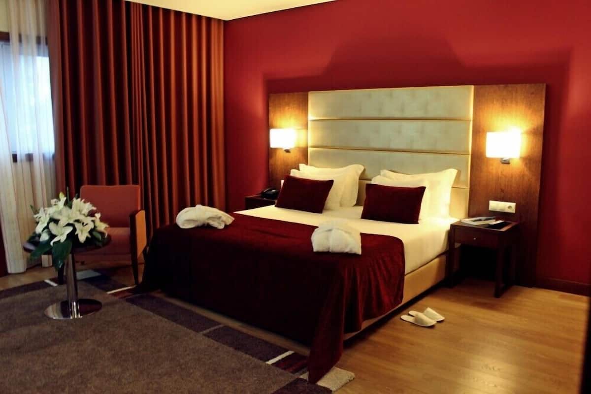 Una habitación de hotel con una cama grande, paredes rojas y suelo de madera.