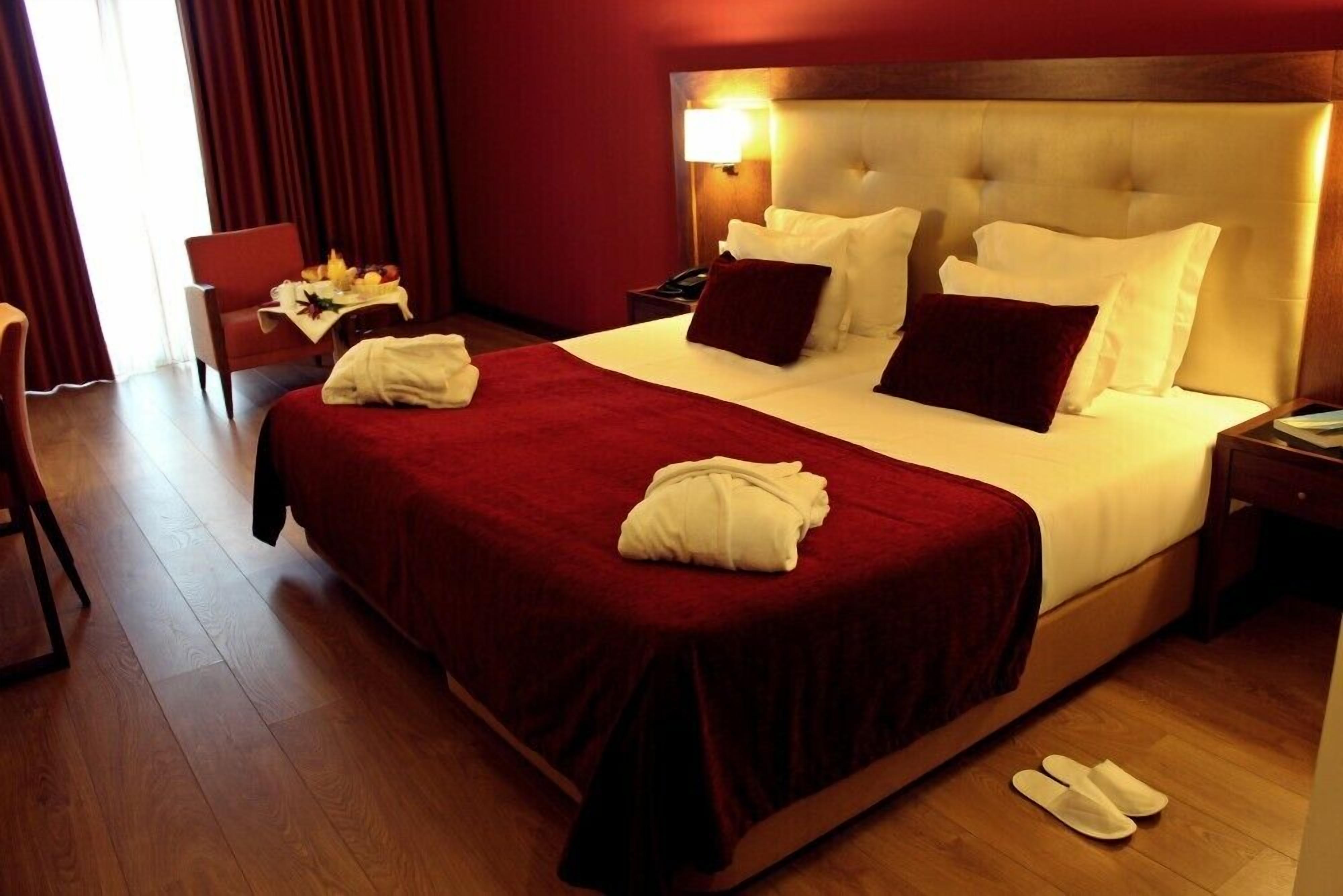 Habitación de hotel con una cama grande, una mesita de noche, una silla y un escritorio con una lámpara.
