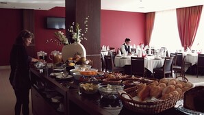 A buffet setup with various food items and a waiter in the background. - Palace Hotel & Spa Termas de S. Miguel (Fornos de Algodres)