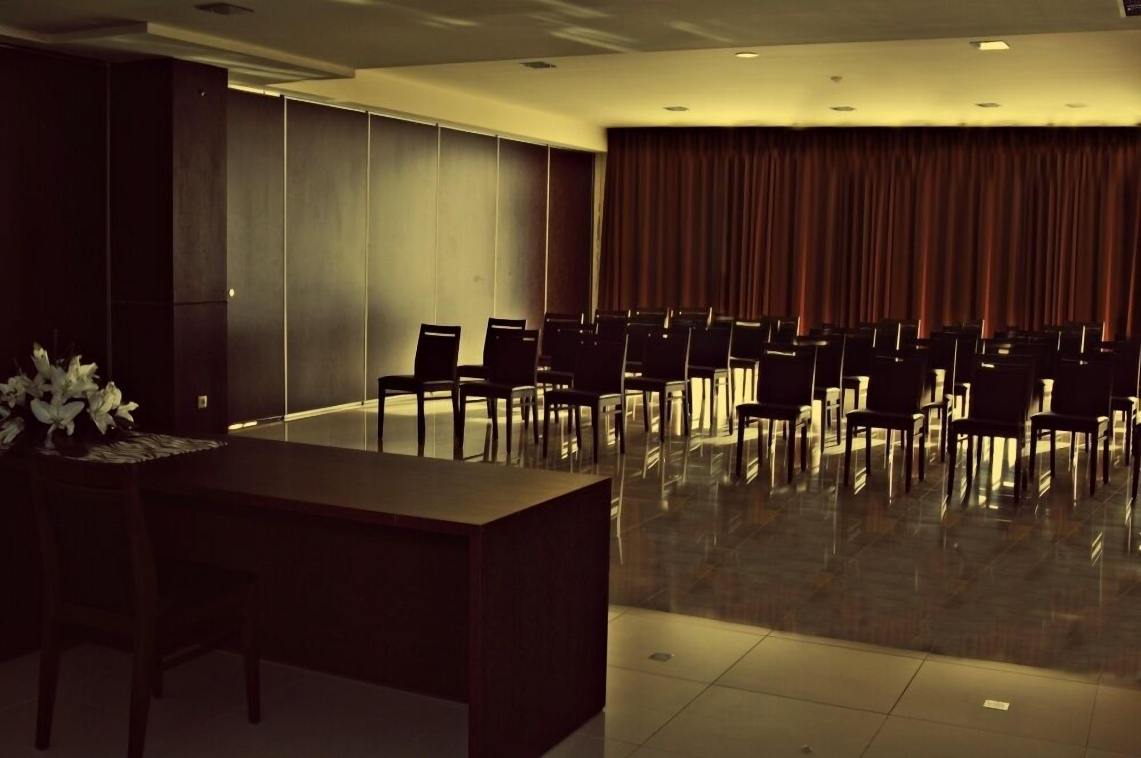 A conference room with a long table, chairs, and a curtain backdrop.