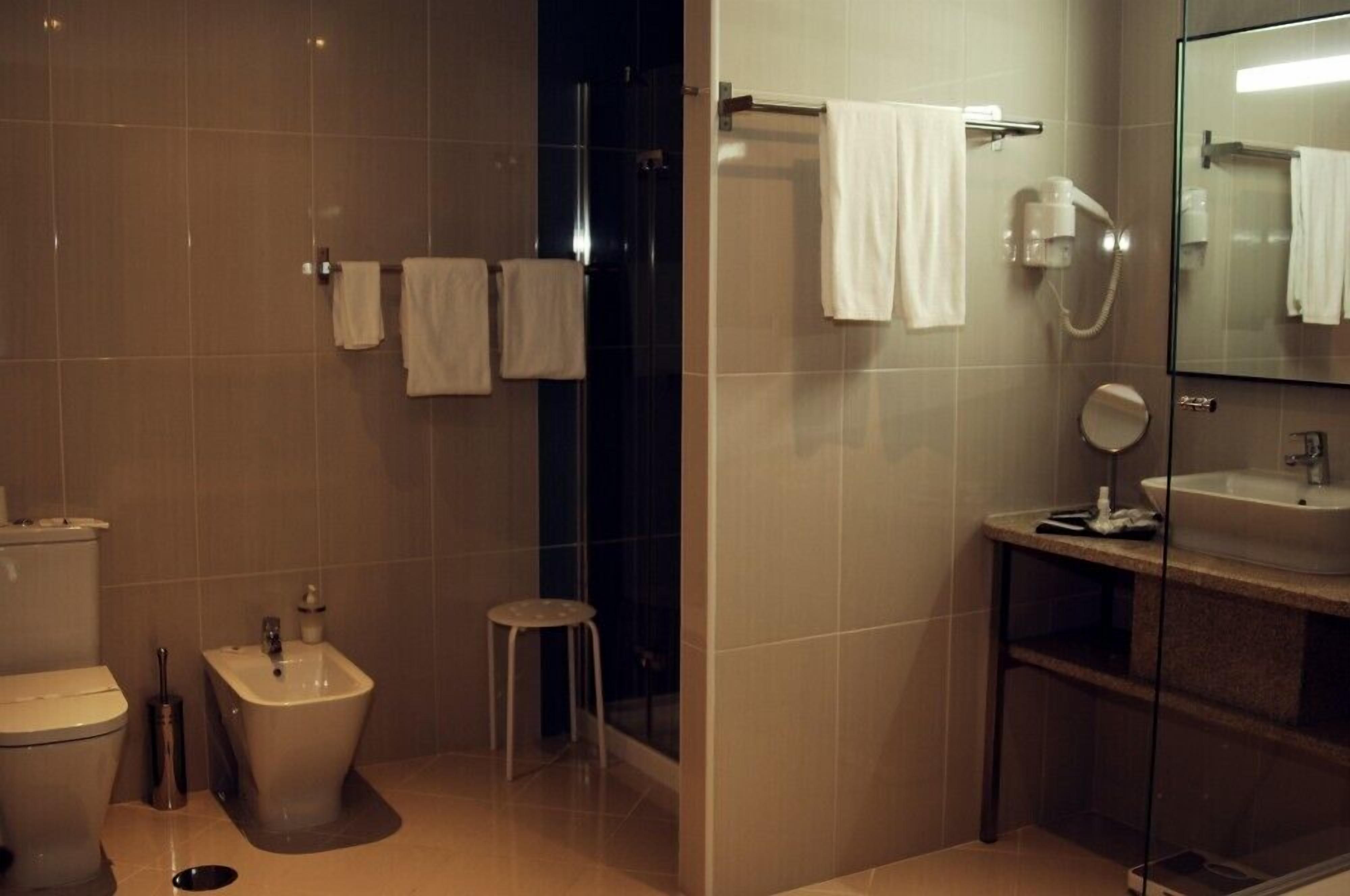 A modern bathroom with a toilet, bidet, and a glass-enclosed sink area.