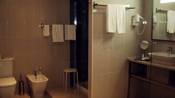 A modern bathroom with a toilet, bidet, and a glass-enclosed sink area.