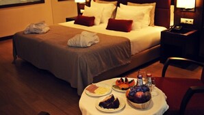 A hotel room with a neatly made bed, a bedside table with a lamp, and a breakfast tray on the floor. - Palace Hotel & Spa Termas de S. Miguel (Fornos de Algodres)
