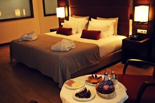 Habitación de hotel con una cama bien hecha, una mesita de noche con lámpara y una bandeja de desayuno en el suelo.