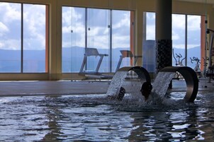 Piscina interior con vistas despejadas a montañas a través de amplios ventanales.