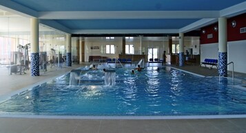 Piscina interior com várias pistas de natação, um toboágua e equipamentos de ginástica.