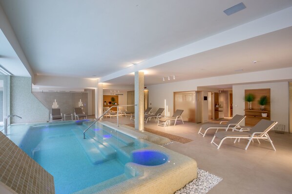 A modern indoor swimming pool with lounge chairs and a spa area. - Hotel Green Park Madama Spa & Wellness (Castel Madama)