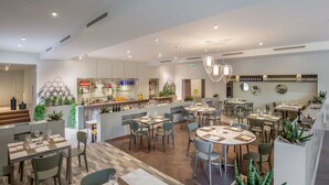Un restaurante moderno con varias zonas de comedor, una barra y una variedad de plantas.