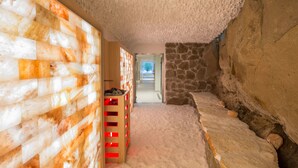 Un pasillo estrecho con techo texturizado, paredes de piedra y un banco de madera con una banda roja.
