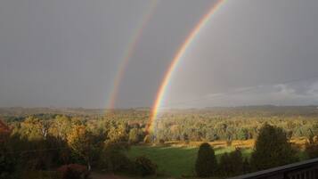 A landscape with two rainbows over a forested area.