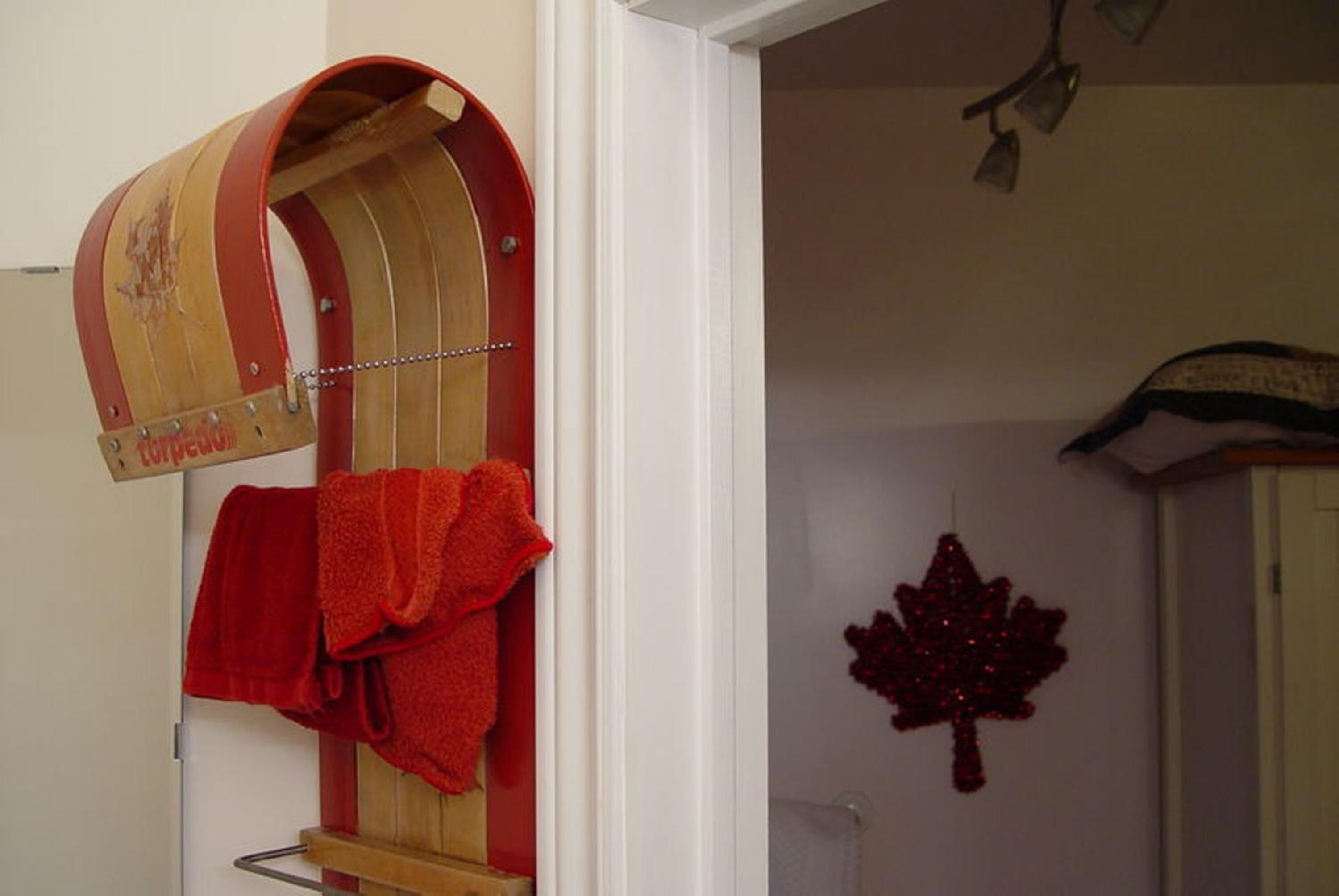 A wooden towel rack with a red towel hanging on it.