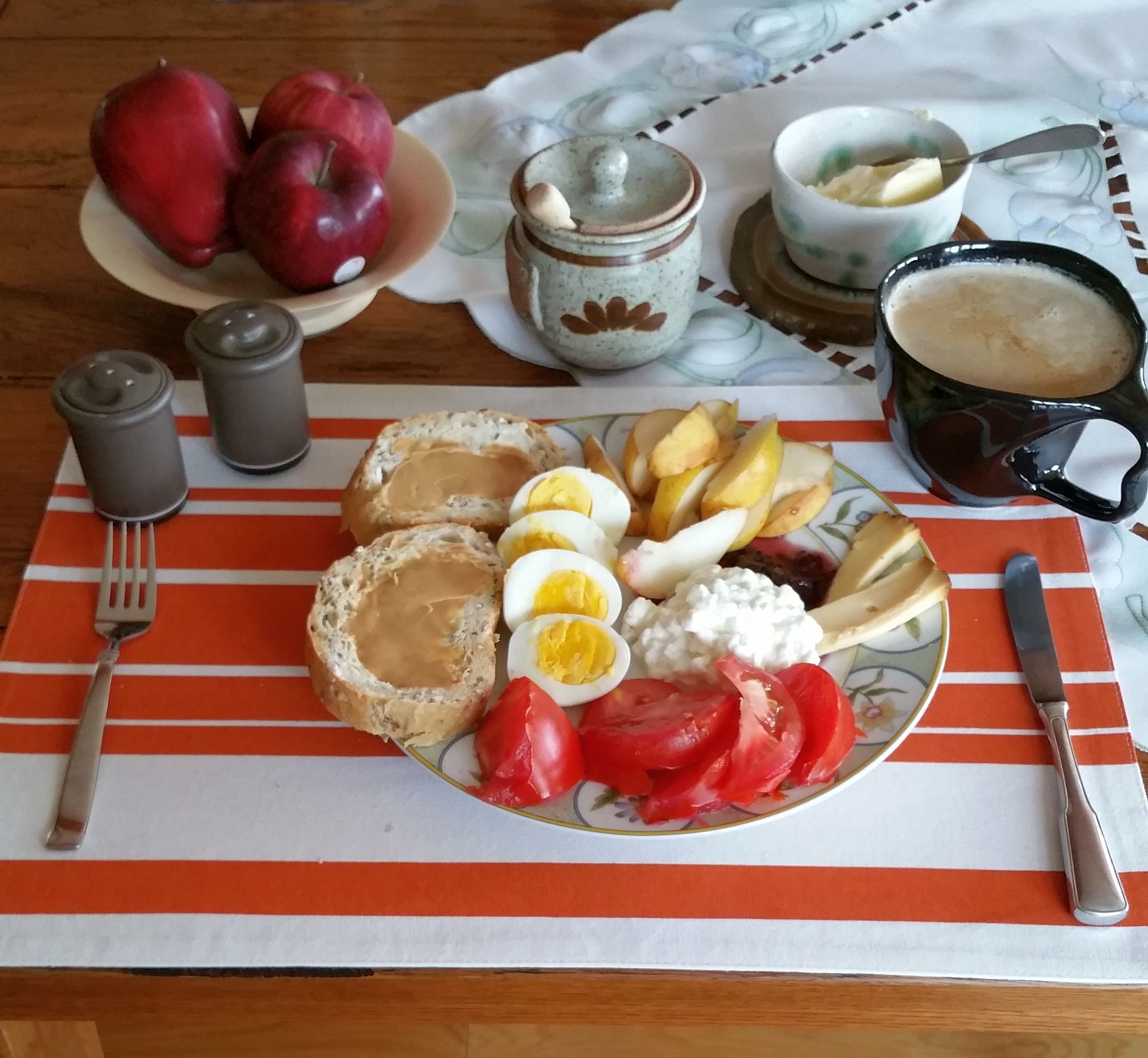 A breakfast plate with eggs, bread, tomatoes, and a cup of coffee.