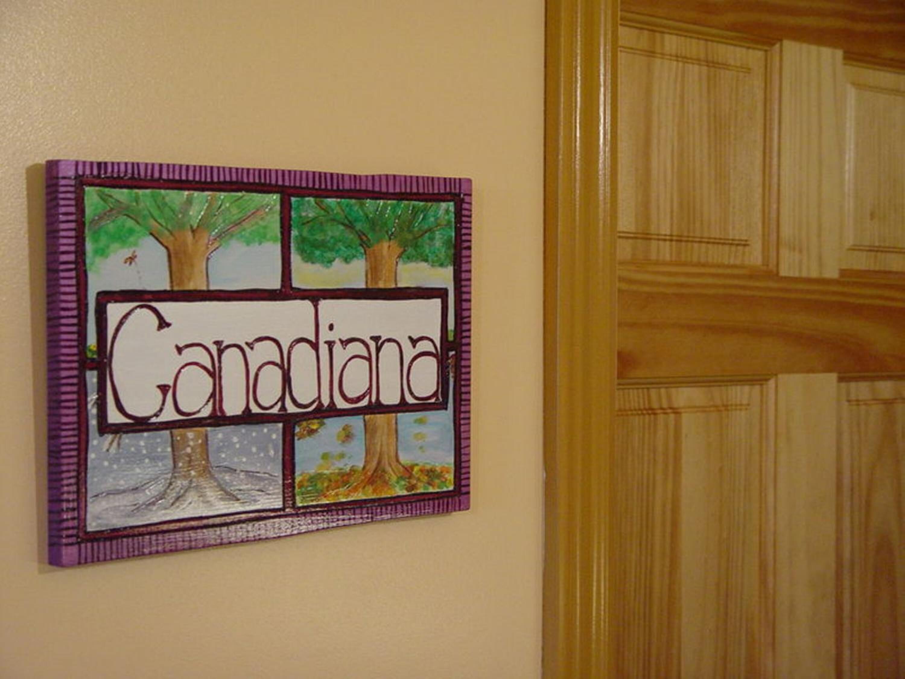 A wall with a framed artwork depicting trees and the word "Canada" in the center.