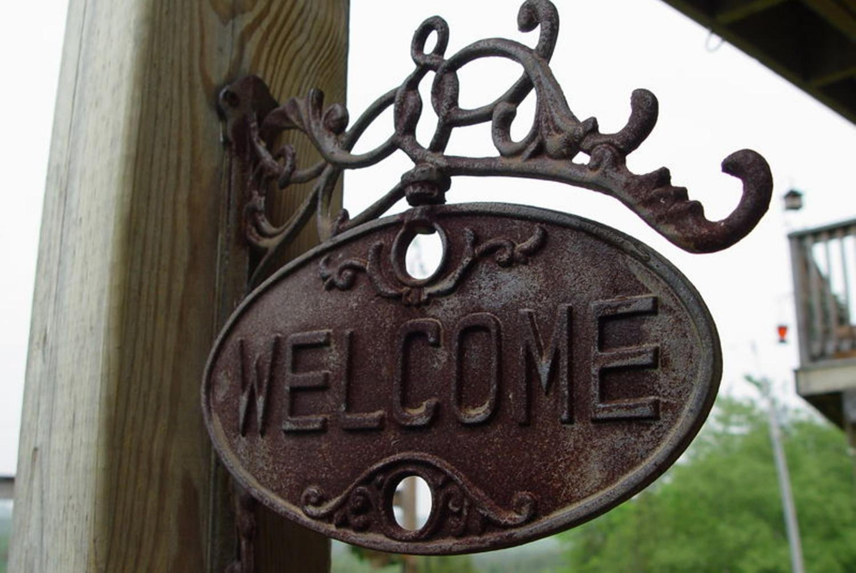 A rustic metal sign with the word "WELCOME" engraved on it.