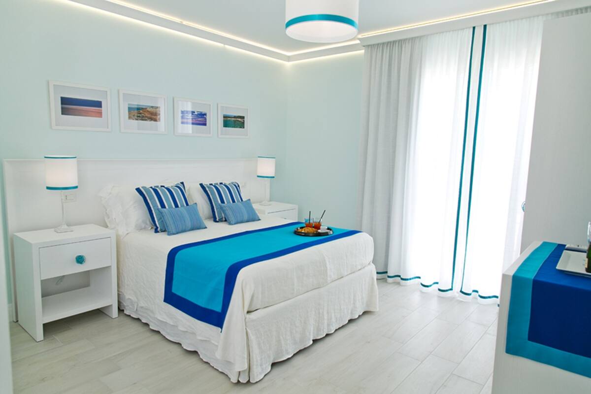 A modern bedroom with a large bed, white nightstands, and a blue accent wall.