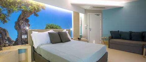 A bedroom with a bed, a sofa, a wall mural, and a nightstand.