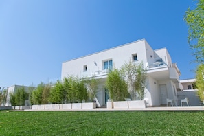 Stylish two-story residence with a minimalist design, set amidst a peaceful lawn and trees.