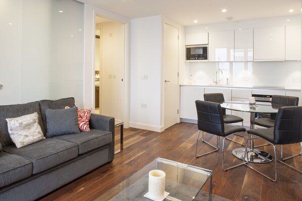 A modern living room with a grey sofa, black chairs, and a glass coffee table.