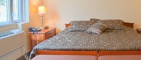 Un dormitorio con una cama, mesitas de noche, una lámpara y una ventana.