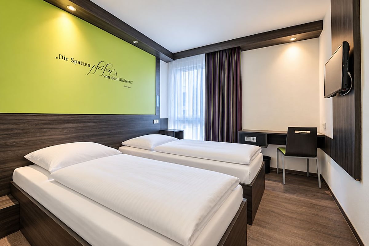 Habitación de hotel con dos camas, un escritorio y una silla.