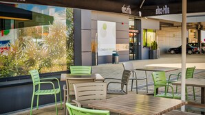 Un área de estar al aire libre con sillas verdes y mesas de madera, un letrero que dice Economy Hotel y vistas a la calle.