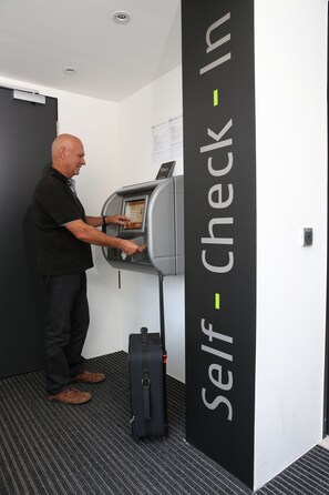 Un hombre utilizando un quiosco de auto-registro en el vestíbulo de un hotel.