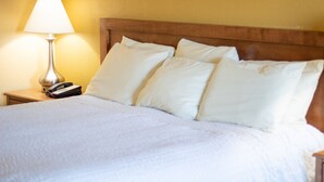 A hotel room with a bed, white bedding, a lamp, and a phone on the nightstand. - Norma Dan Motel - Near Dolly Parton's Stampede Dinner Attraction (Pigeon Forge)