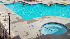 A swimming pool area with lounge chairs and a hot tub, surrounded by a building with a tiled roof. - Norma Dan Motel - Near Dolly Parton's Stampede Dinner Attraction (Pigeon Forge)