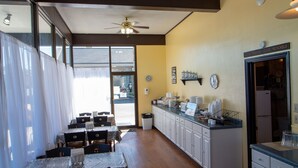 A dining area with tables and chairs, a kitchen area with a refrigerator and counter, and a ceiling fan. - Norma Dan Motel - Near Dolly Parton's Stampede Dinner Attraction (Pigeon Forge)