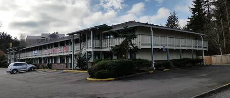 A motel with a two-story structure, a parking lot, and a small parking garage.