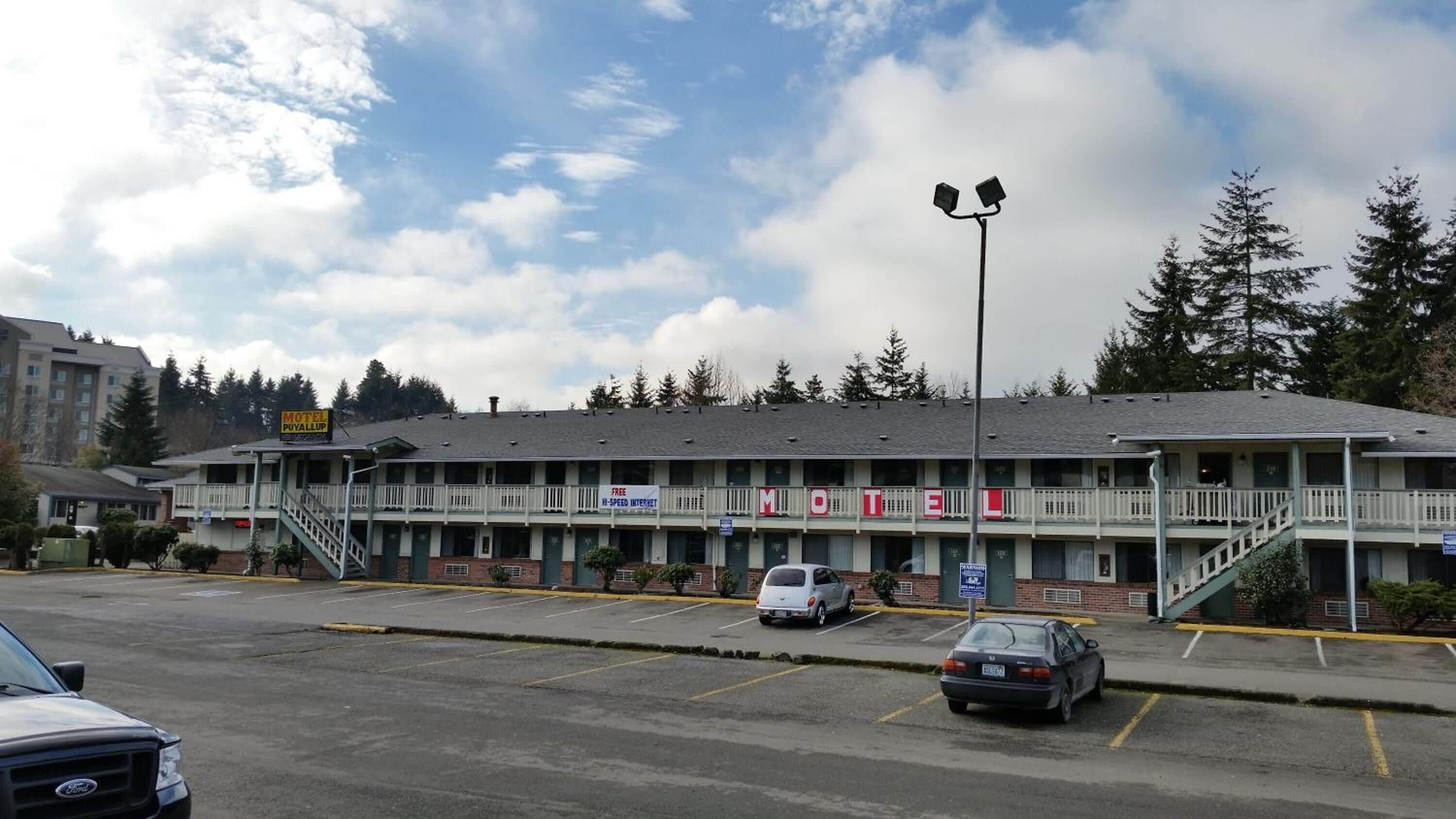 A motel with a two-story structure, a covered parking area, and a visible staircase leading to the entrance.