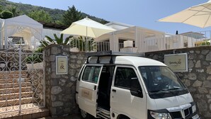 Una camioneta blanca estacionada frente a un muro de piedra con un letrero que dice 'Bottola del Re'.