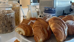 Un bufé de desayuno con pastelería, una máquina de café y frascos de salsas.