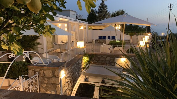 Un hotel moderno con mesas al aire libre, paredes de piedra y un patio bien iluminado.