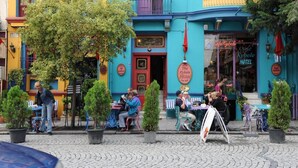 Exterior de un hotel colorido con asientos al aire libre y un letrero que dice 