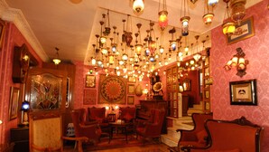 Una habitación cálidamente iluminada con varias lámparas colgantes, una imponente escalera y una decoración tradicional.