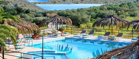 A pool area with lounge chairs and a view of a lake.