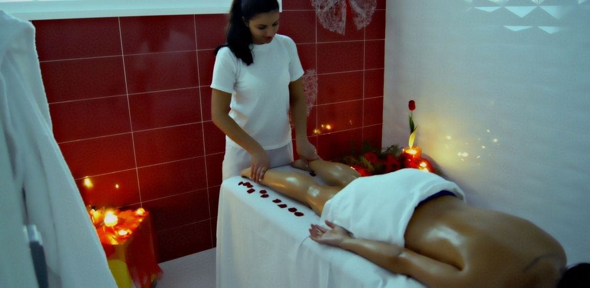 A massage therapy session in a room with red tiled walls and a white ceiling.