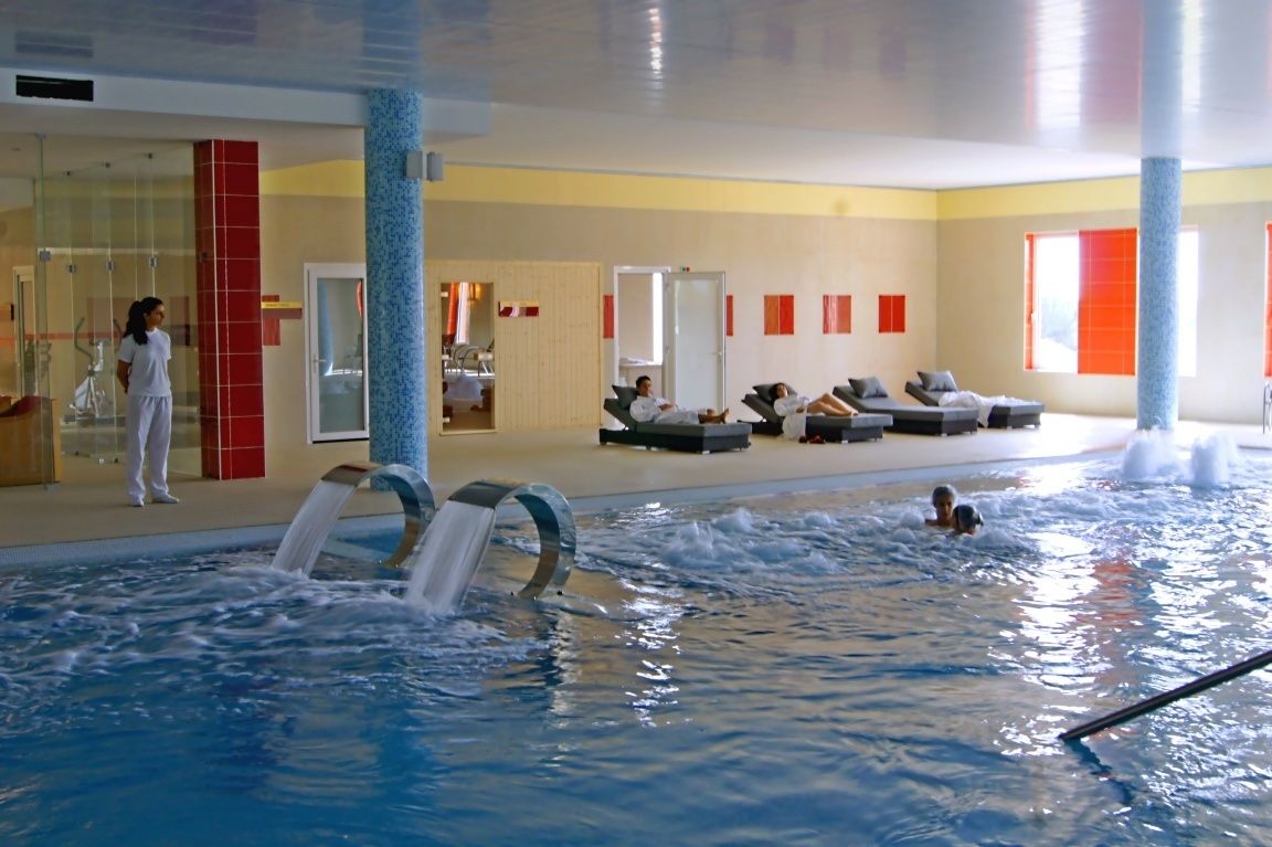 Una piscina interior amb diverses línies, un vestidor i una zona de relaxació amb gandules.