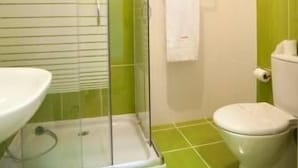 Un baño con cabina de ducha de vidrio, inodoro y lavamanos.