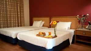 Una habitación de hotel con dos camas, una bandeja de desayuno y un florero con flores.